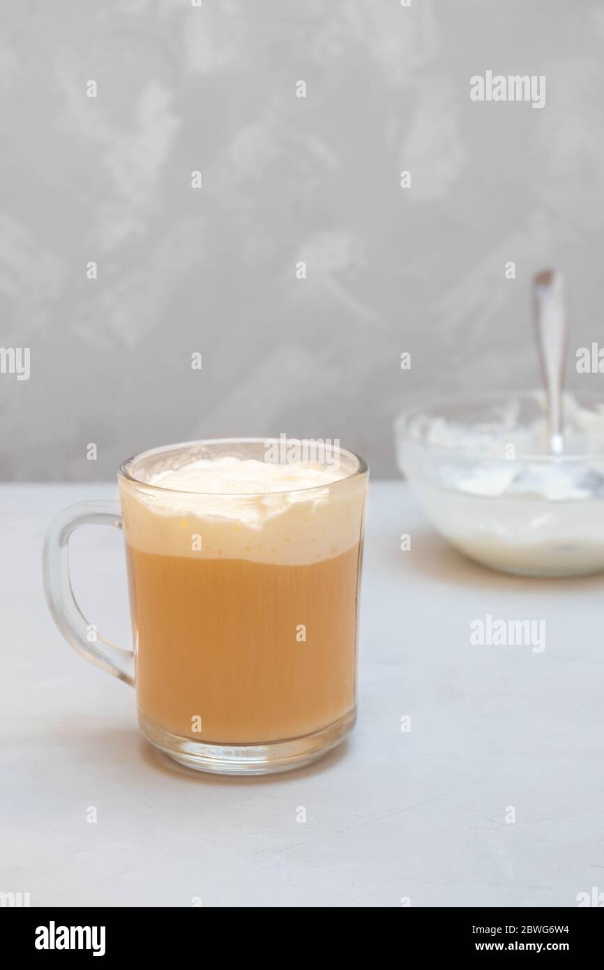 Tasse Käse Kaffee auf grauem Hintergrund. Schwarzer Tee mit Frischkäse Schaum. Milch Kaffee Stockfoto