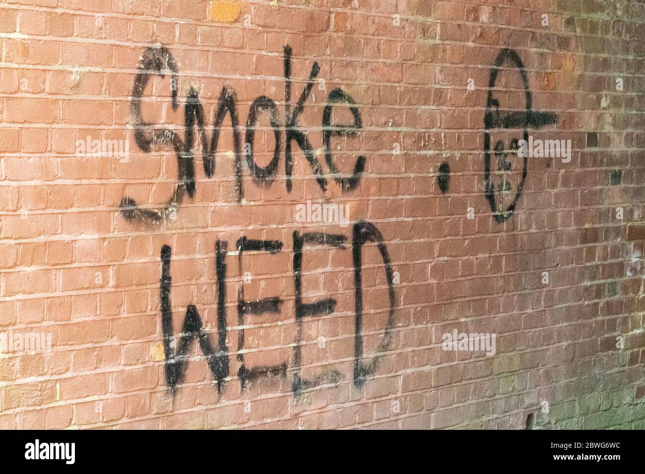 Graffiti mit dem Spruch Smoke Weed auf einer Ziegelbahnbrücke, Großbritannien Stockfoto