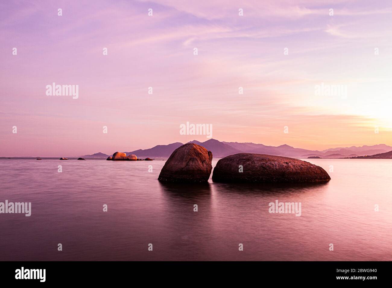 Felsen im Wasser vom Palmeiras Beach bei Sonnenuntergang gesehen. Florianopolis, Santa Catarina, Brasilien. Stockfoto