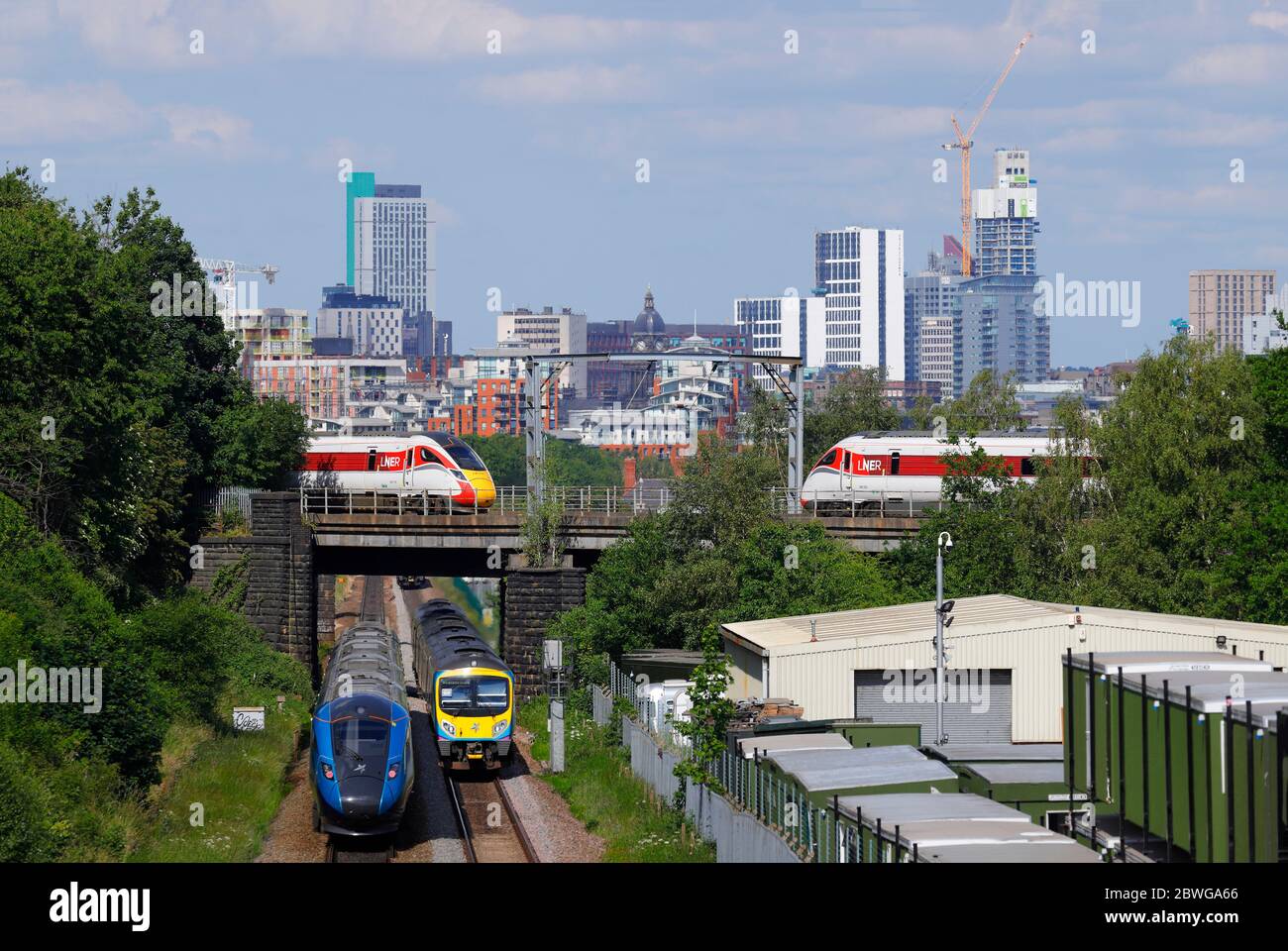 Ein zusammengesetztes Bild von Zügen, die in Leeds über und unter einer Eisenbahnbrücke fahren. Yorkshire's neuestes höchstes Gebäude, 'Altus House', das im Bau ist Stockfoto