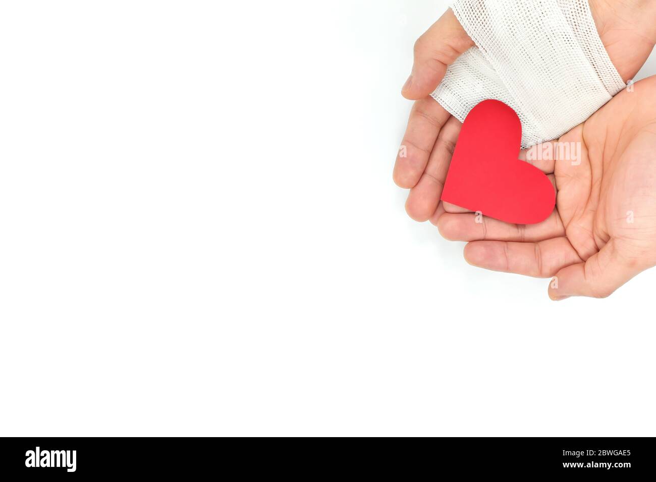 Eingekuppelte Hände mit Verband, der ein rotes Herz hält. Opfer, Organspende, Nächstenliebe und echte Liebe und Güte. Stockfoto