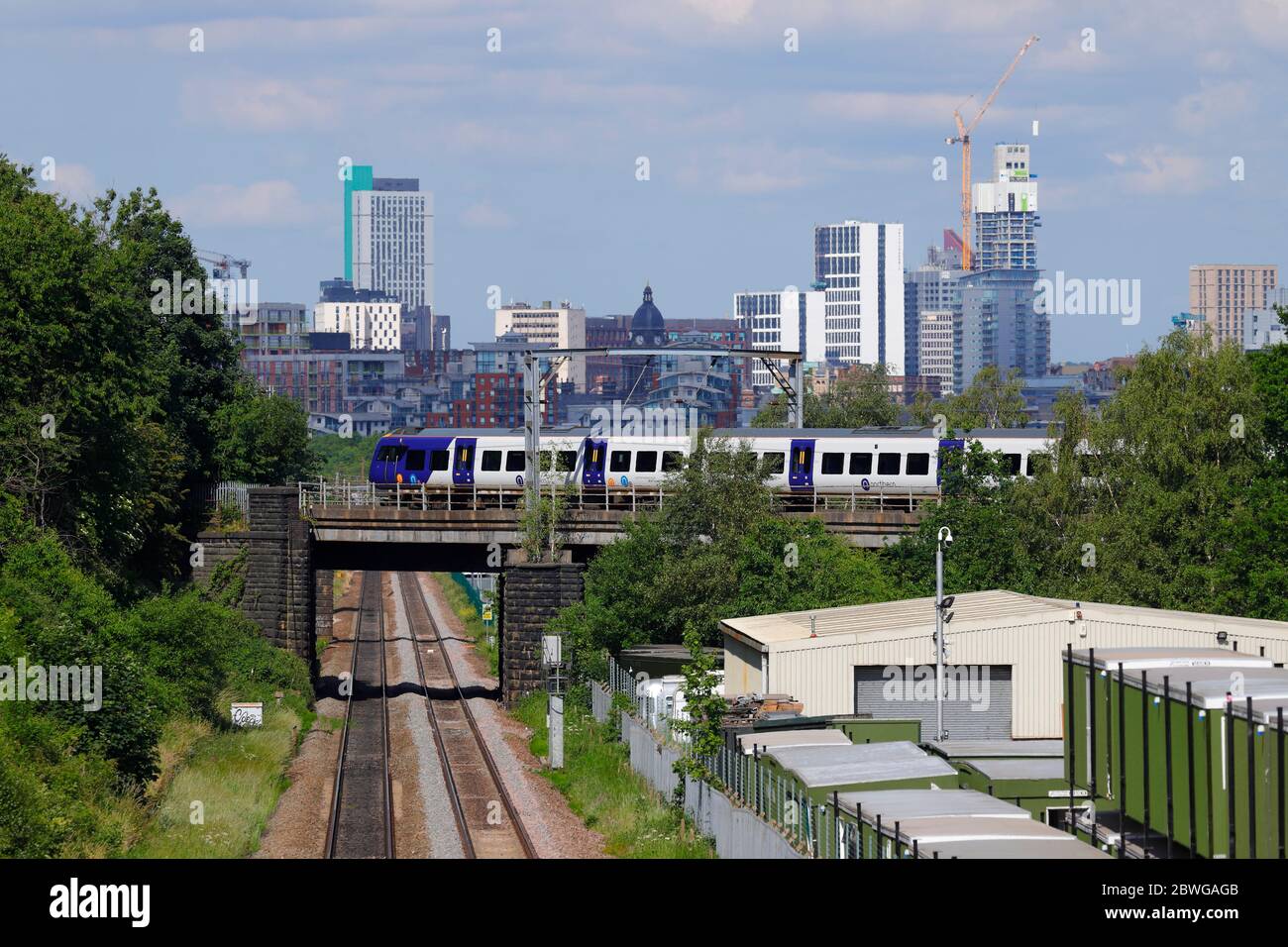 Ein Zug der Bahnklasse 331 von Northern Rail fährt vor der Skyline von Leeds vorbei Stockfoto