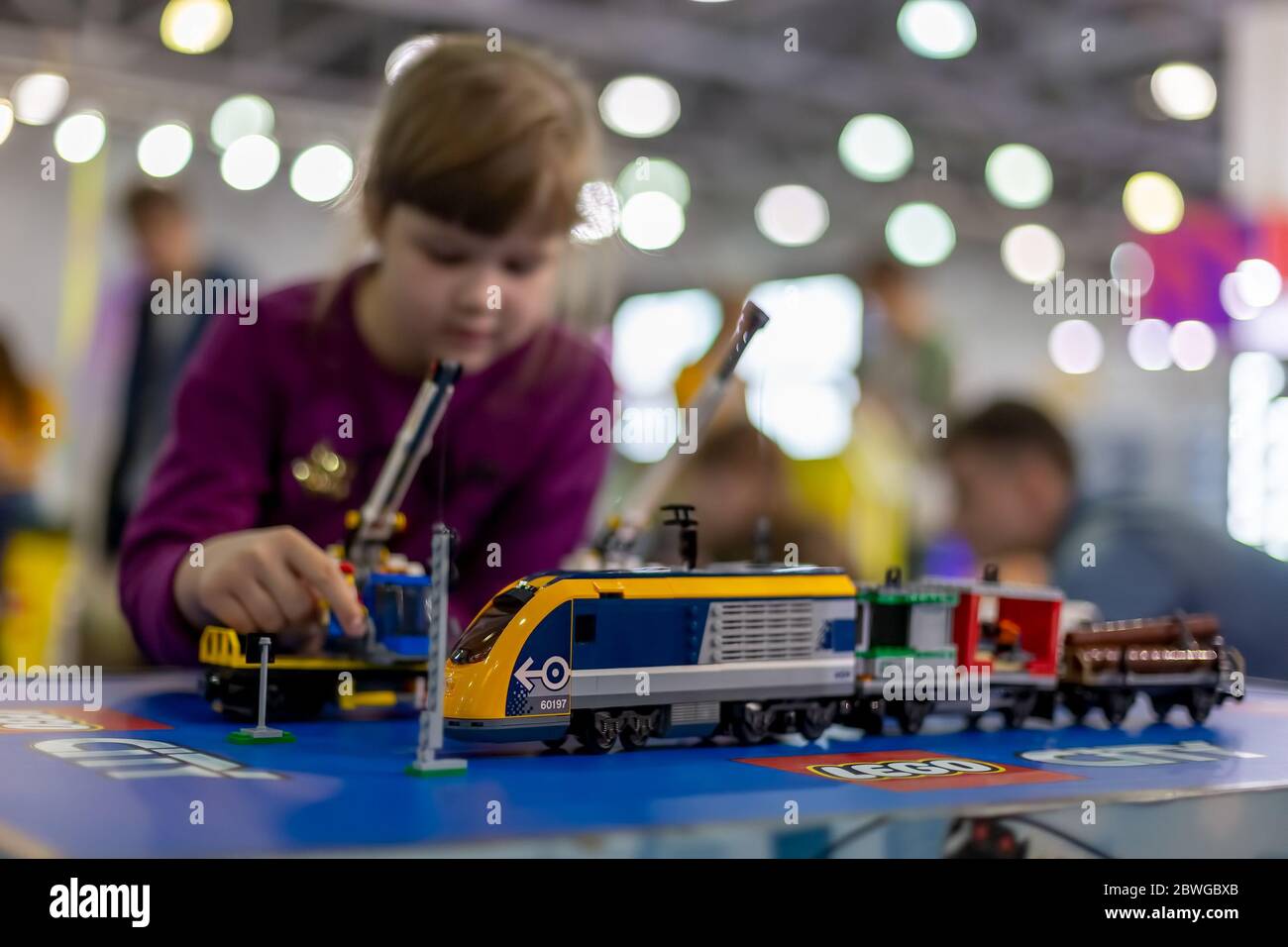 Moskau, Russland - 04. Oktober 2019: Gelber elektrischer lego-Zug mit Kranen. Im Hintergrund spielt das Kind mit ihm in Unschärfe Stockfoto