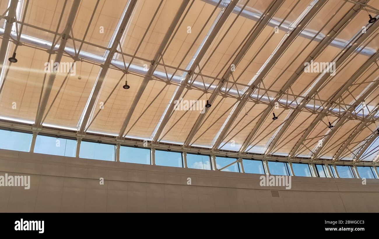 Geschwungenes Dach mit Fenstern eines großen Einkaufszentrums im Innenbereich. Moderne Deckenkonstruktion aus Metall und Glas Stockfoto