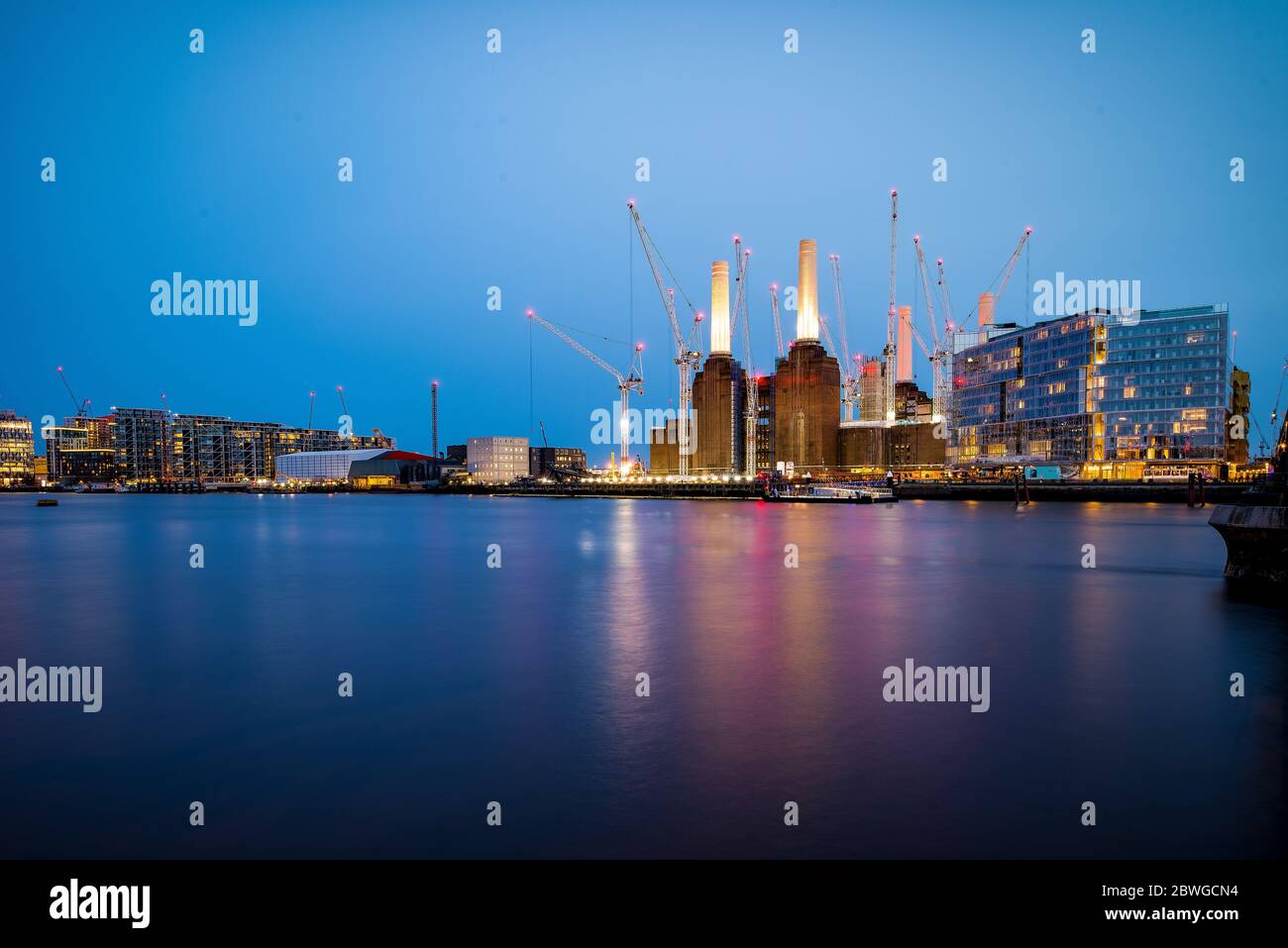 Blick auf die Abenddämmerung von der anderen Seite der Themse auf das Regenerationskonzept des Kraftwerks Battersea während des Baus, mit Kränen. Stockfoto