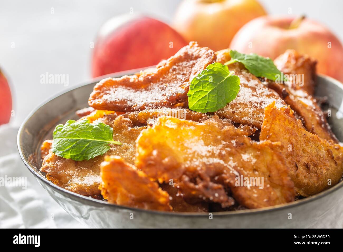 Fein gebratene Apfelpfannkuchen, bestreut mit Vanillezucker und Zimt, gekrönt mit Minzblättern Stockfoto
