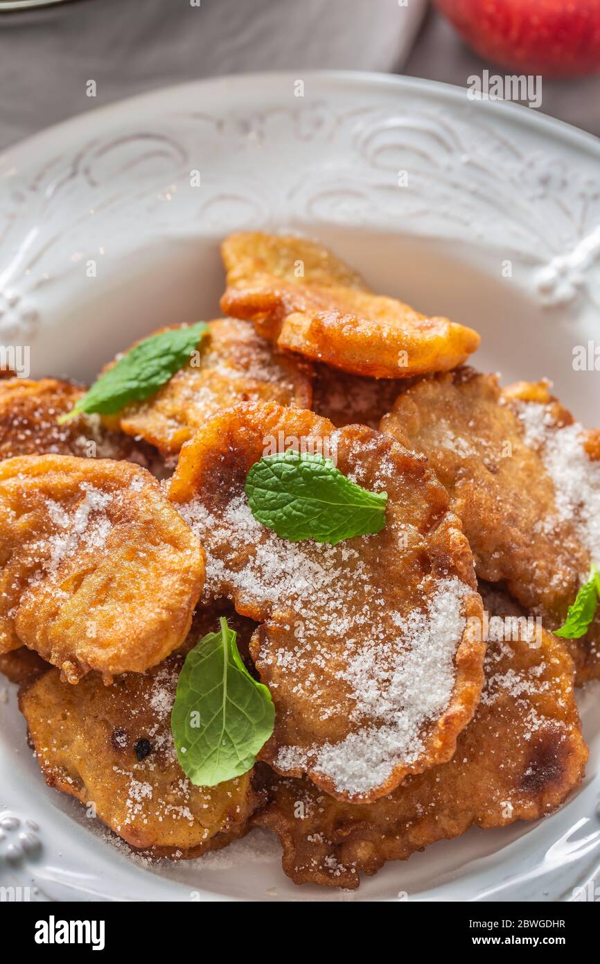 Fein gebratene Apfelpfannkuchen, bestreut mit Vanillezucker und Zimt, gekrönt mit Minzblättern Stockfoto