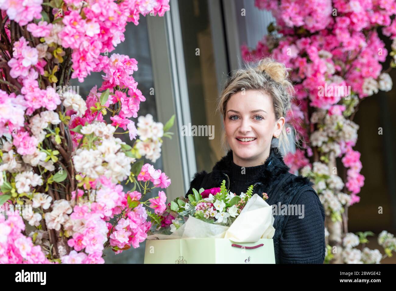 Eine hübsche junge Floristin, umgeben von Blumen außerhalb ihres Geschäfts in der kürzlich umbauten Battersea Power Station Area im Südwesten Londons. Stockfoto