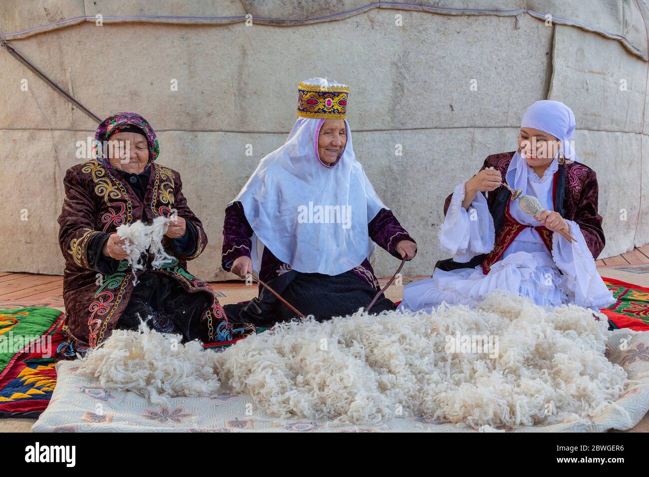 Kasachische ältere Frauen, die die Wolle flauschig machen und spinnen, in Almaty, Kasachstan Stockfoto