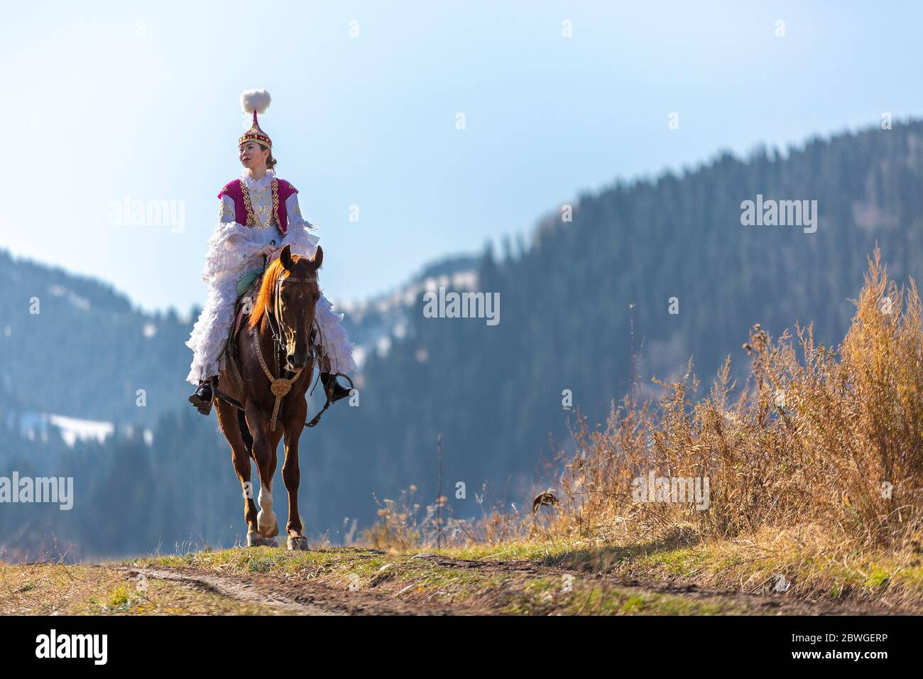 Kasachische Frau in Nationaltrachten, die auf dem Pferd reitet, in Almaty, Kasachstan Stockfoto