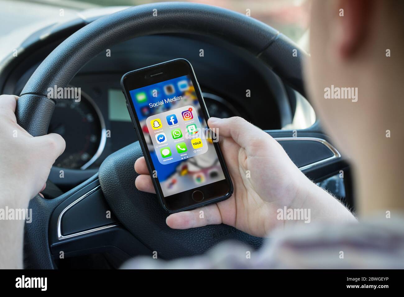 Teenager Fahrer SMS und Blick auf Social Media auf seinem Handy während der Fahrt in Großbritannien. (Bild nach Modell gestellt) Stockfoto