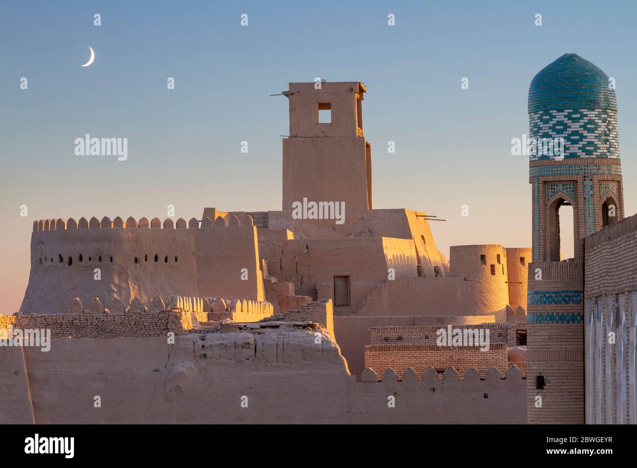 Turm und die alten Mauern der antiken Stadt Chiwa mit Halbmond am Himmel, Usbekistan Stockfoto