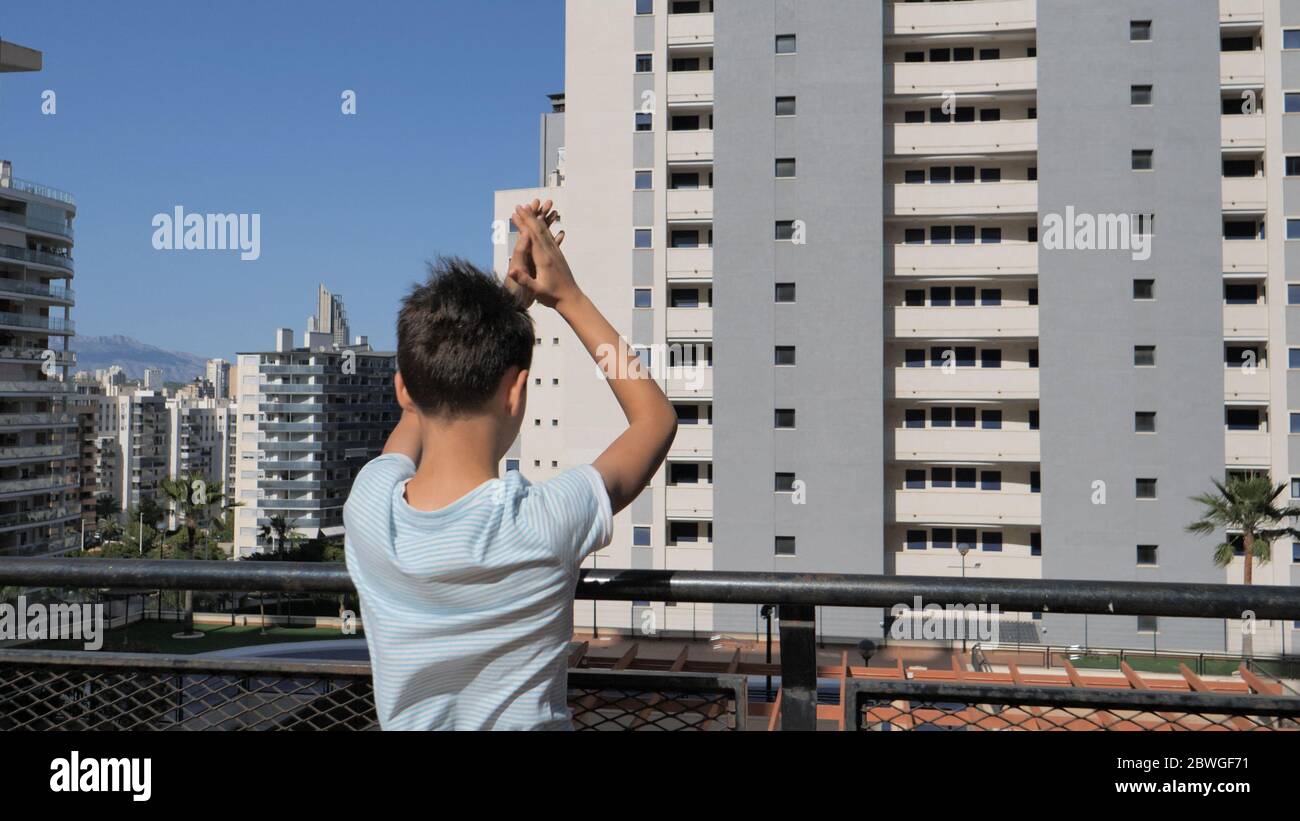 Kind klatscht Hände, applaudieren von Terrasse Balkon, um Ärzte, Krankenschwestern, Krankenhausmitarbeiter während Coronavirus Covid-19 Pandemie Quarantäne zu unterstützen Stockfoto