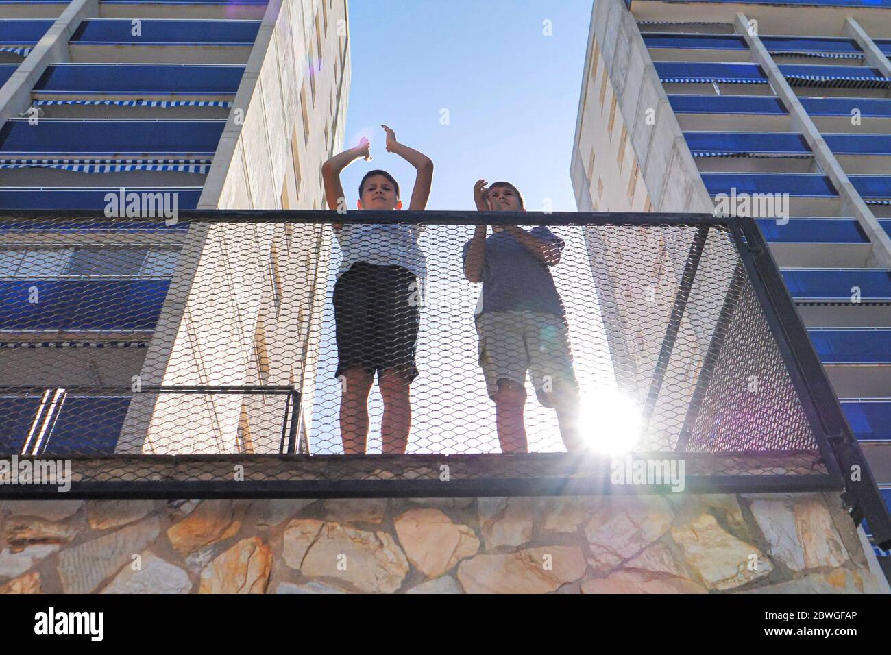 Kinder klatschen mit den Händen, applaudieren vom Balkon der Terrasse, um Ärzte, Krankenschwestern, Krankenhausangestellte während der Coronavirus Covid-19 Pandemie Quarantäne zu unterstützen Stockfoto