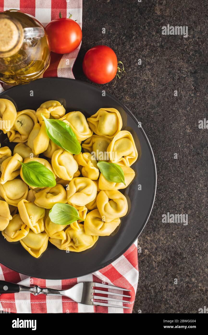 Tortellini Pasta. Italienische gefüllte Pasta mit Basilikumblättern auf dem Teller. Draufsicht. Stockfoto