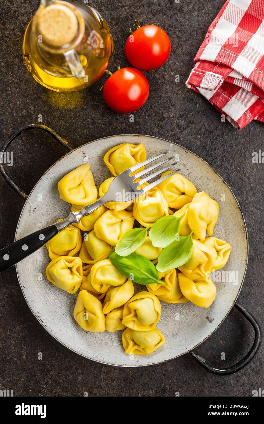 Tortellini Pasta. Italienische gefüllte Pasta mit Basilikumblättern auf der Pfanne. Draufsicht. Stockfoto