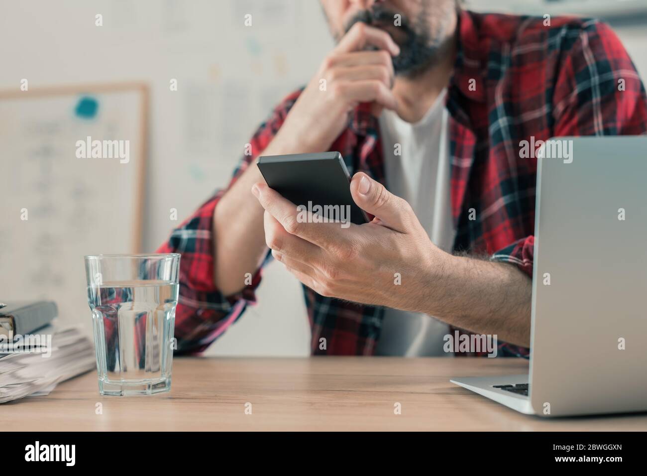 Besorgt Freiberufler Lesen von SMS auf dem Mobiltelefon in seinem kleinen Unternehmen Home Office, selektive Fokus Stockfoto