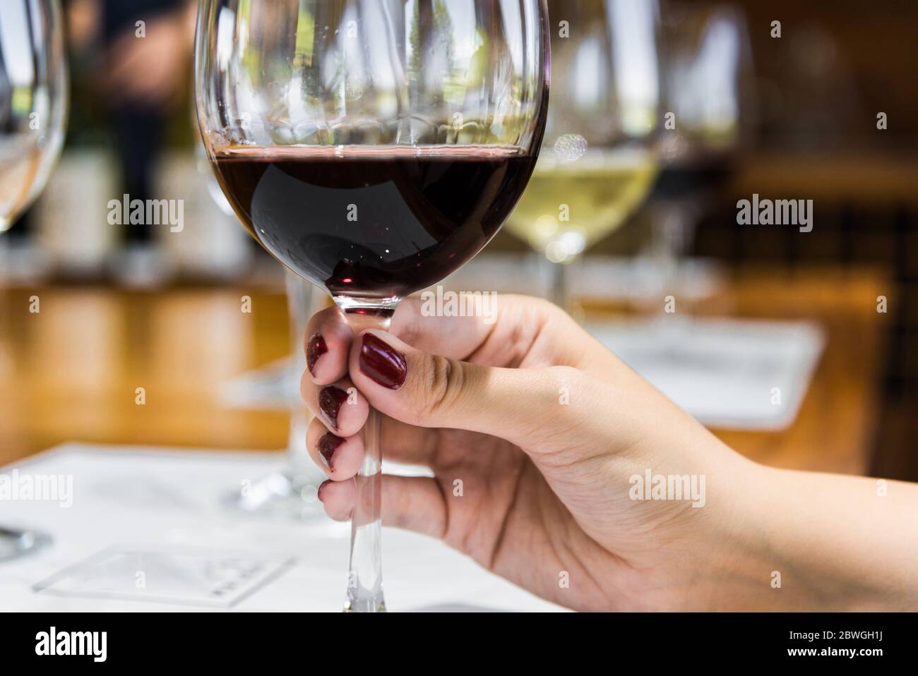 Eine junge Frau, die ein Weinglas mit Rotwein hält Stockfotografie - Alamy