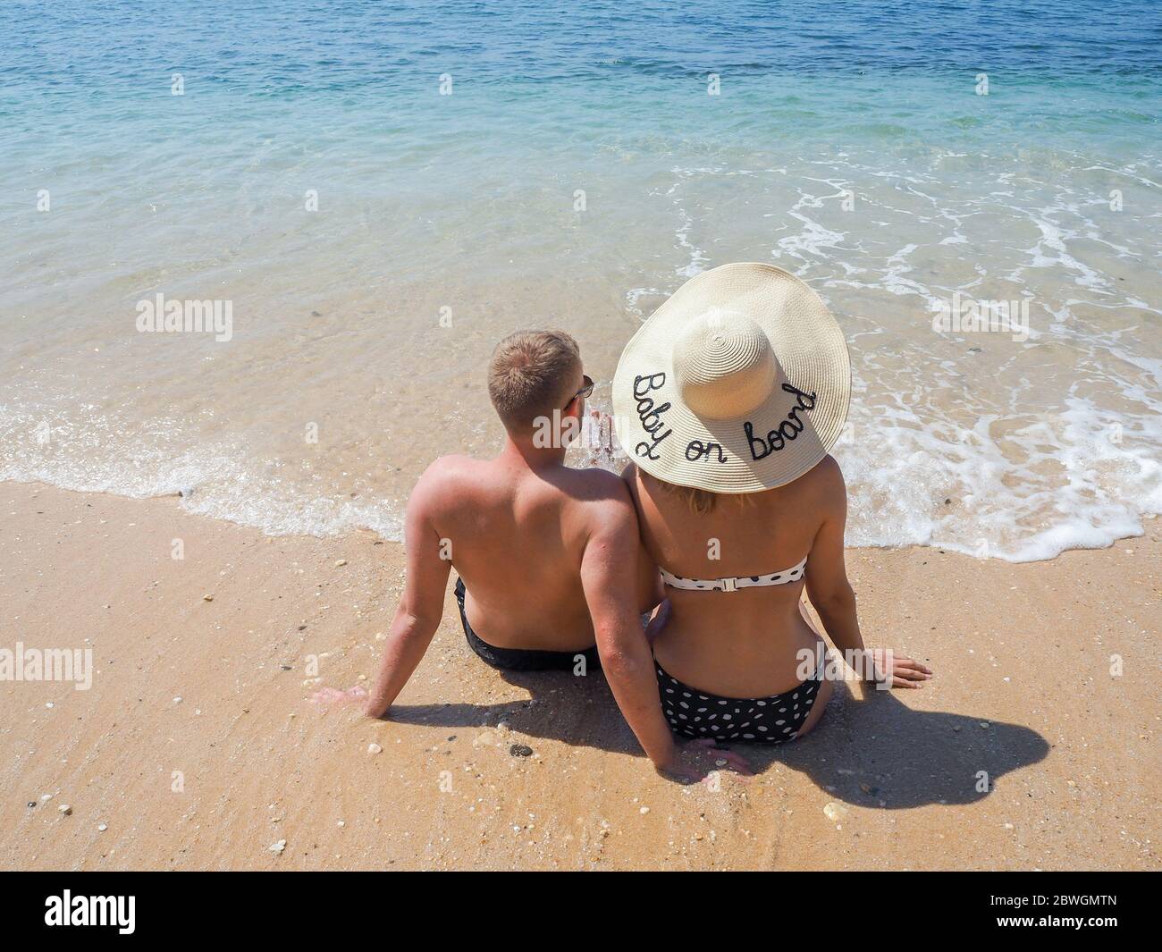 Schwangerschaftsansage am Strand, 'Baby on Board' Hut Stockfoto