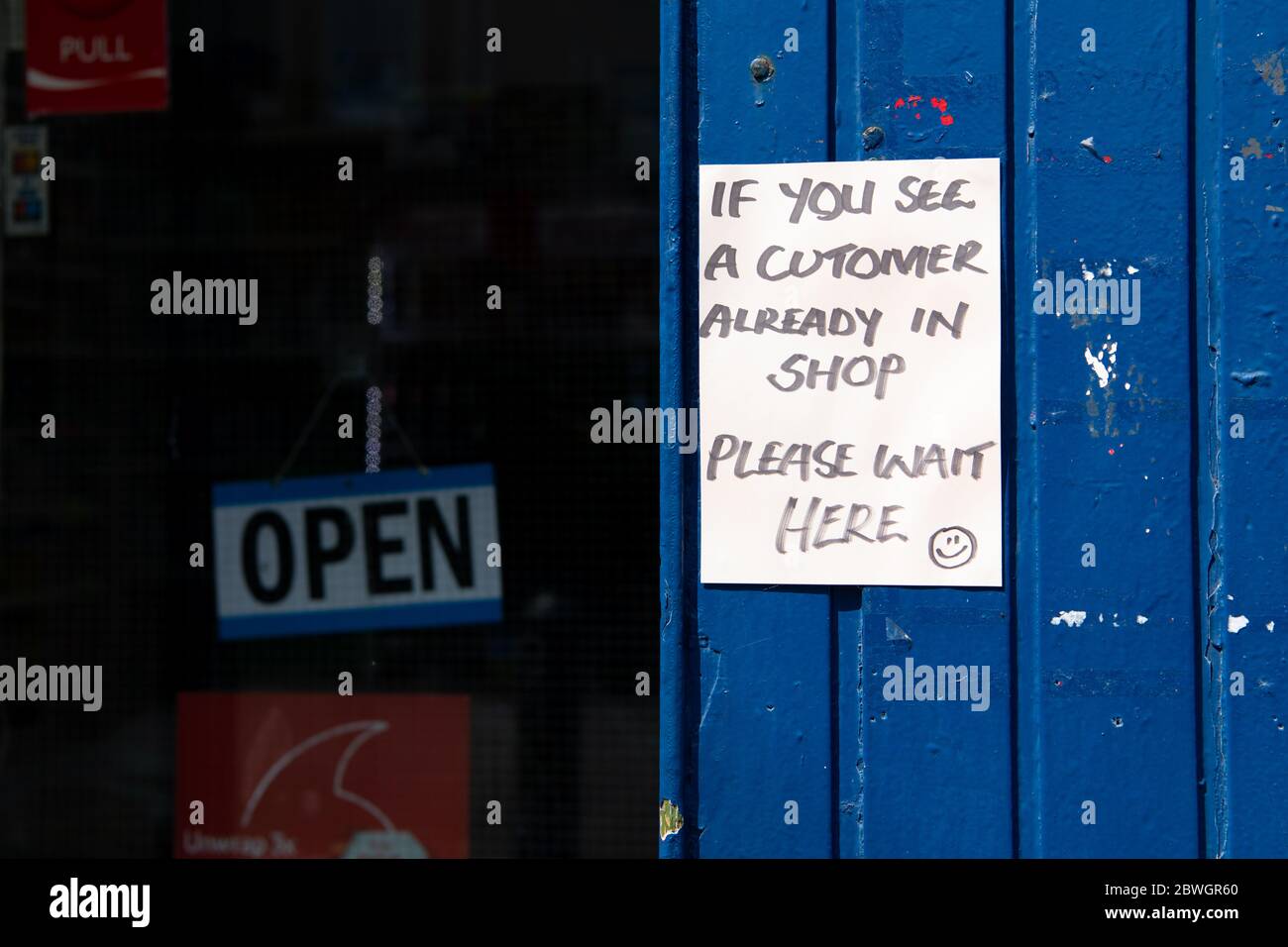 Kleiner Laden während der Coronavirus-Pandemie - Schild draußen Begrenzung Kunden auf eine nach der anderen, Shawlands, Glasgow, Schottland, Großbritannien Stockfoto