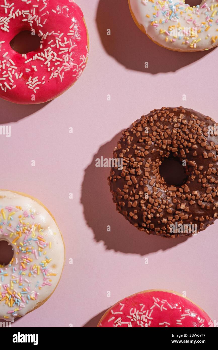 Schokolade, rosa und Vanille Donuts mit Streuseln, süß glasiert Dessert-Essen auf rosa minimal Hintergrund, Draufsicht Stockfoto