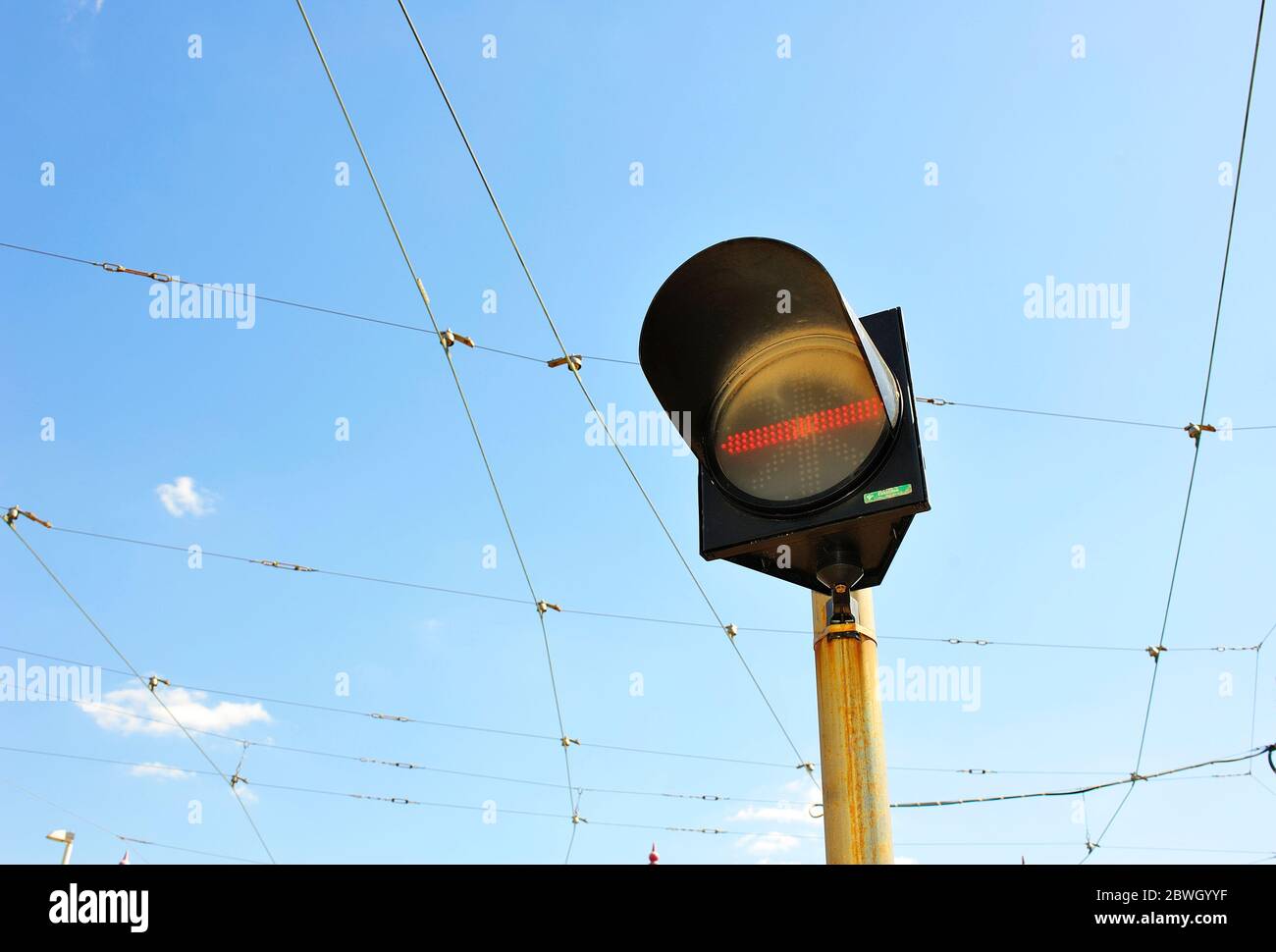 Halten Sie die Fahrbahn an der Ampel gegen die Oberleitungen und den Himmel Stockfoto