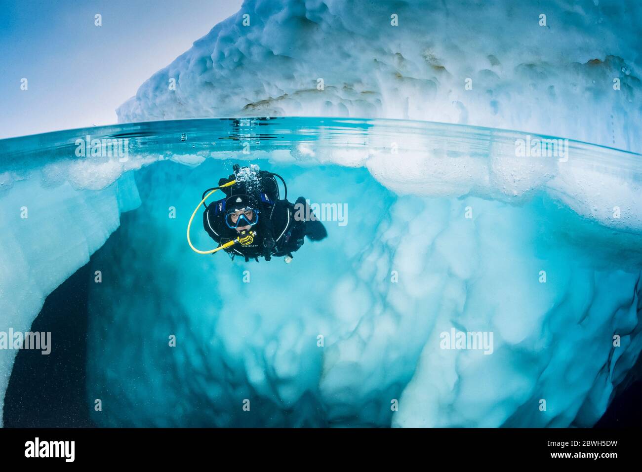 Spit Bild eines Scuba Diver tauchen in der Nähe von einem Eisberg, nur im Frühling, wenn der Winter langsam nachlässt, sind die Eis-kalten Gewässern geeignet für Stockfoto