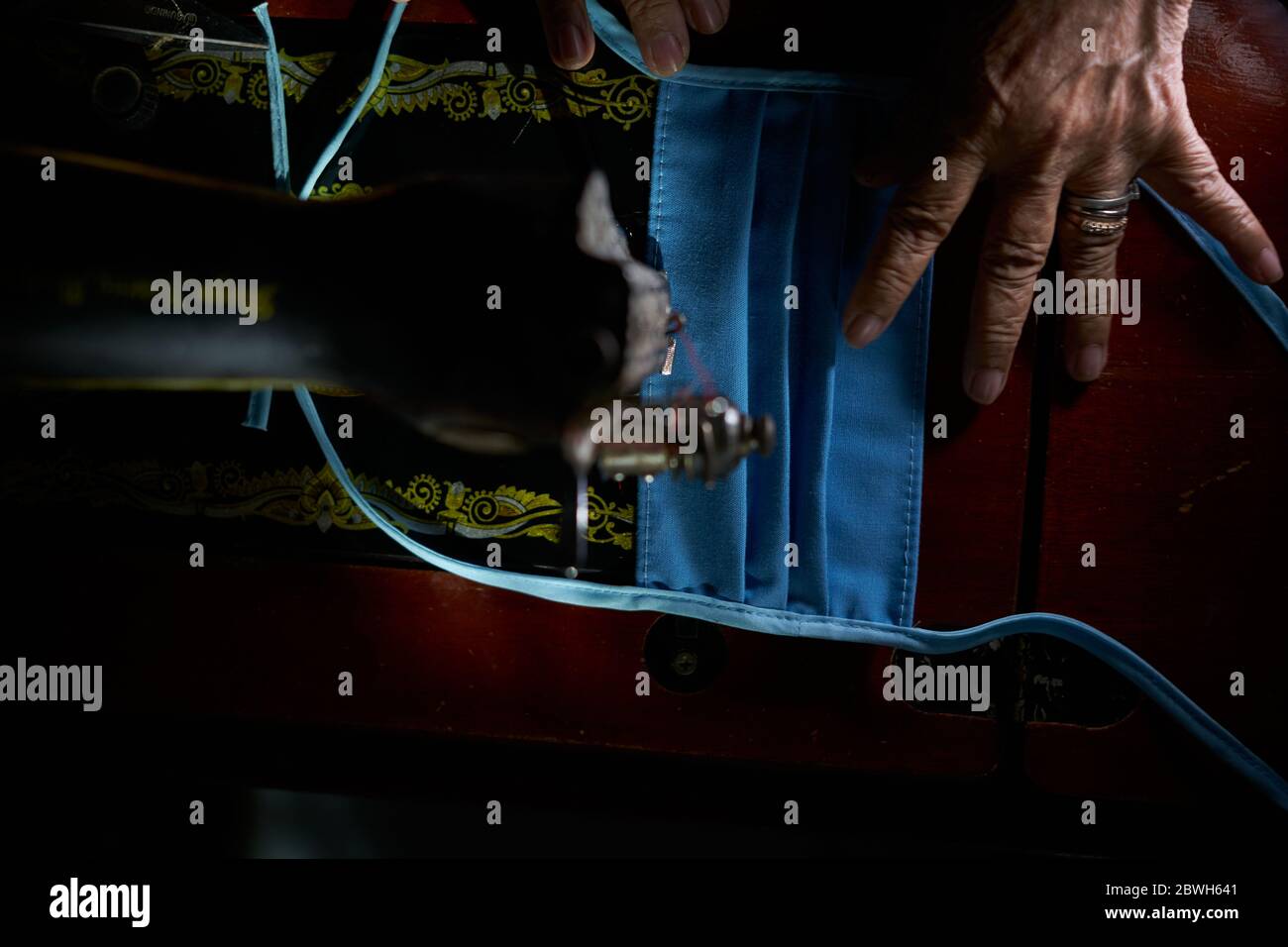 Nahaufnahme der Frau, die selbstgemachte Schutzmaske mit alter Nähmaschine macht Stockfoto