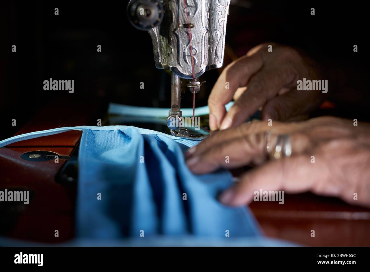 Nahaufnahme der Frau, die selbstgemachte Schutzmaske mit alter Nähmaschine macht Stockfoto