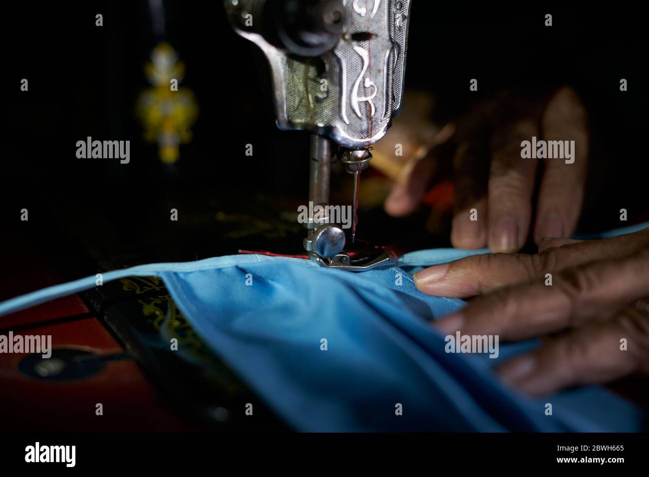 Nahaufnahme der Frau, die selbstgemachte Schutzmaske mit alter Nähmaschine macht Stockfoto