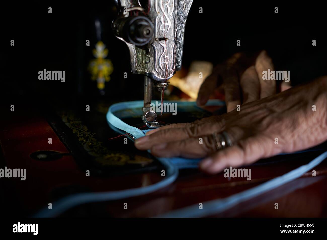 Nahaufnahme der Frau, die selbstgemachte Schutzmaske mit alter Nähmaschine macht Stockfoto