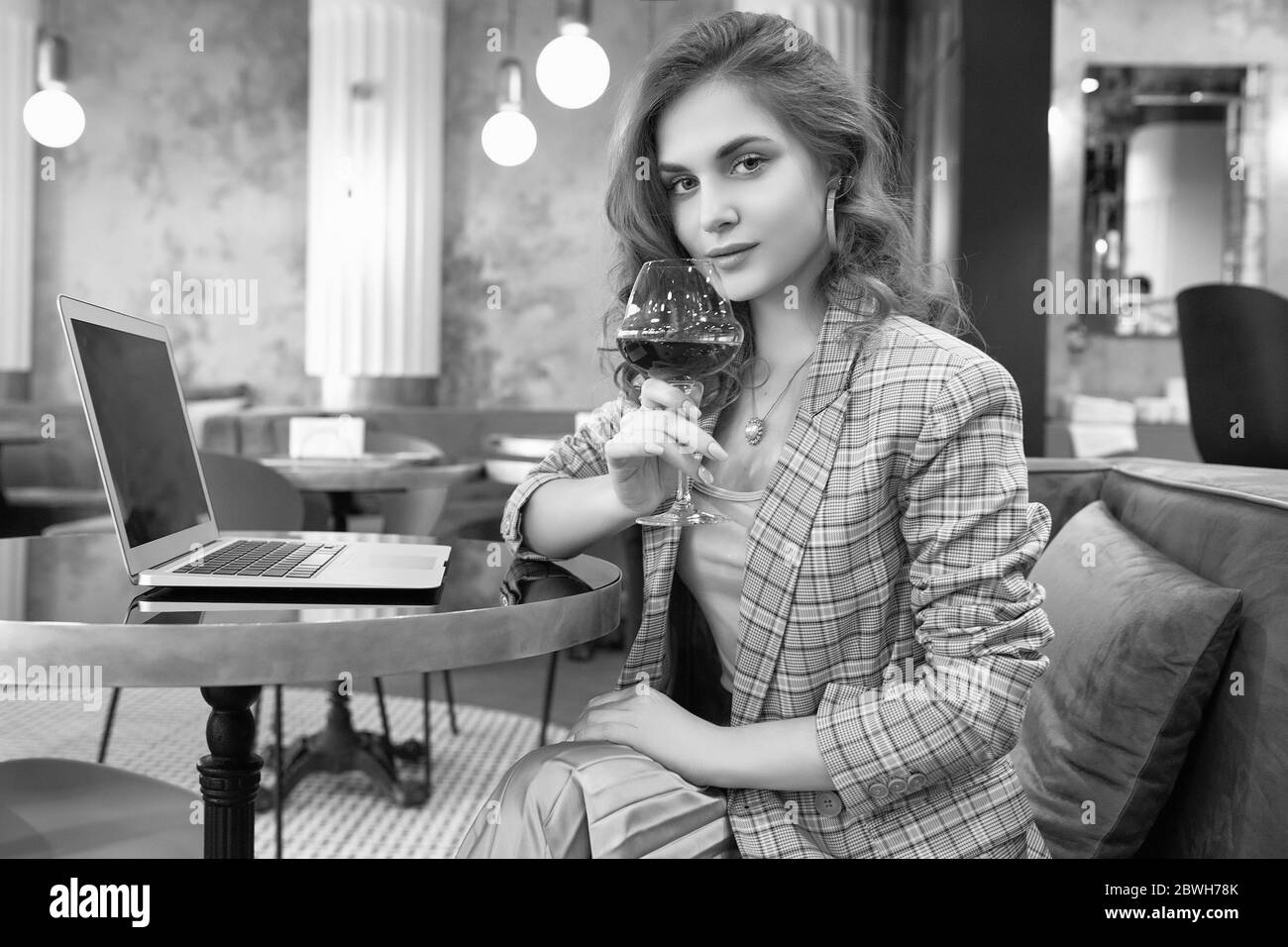 Porträt der selbstbewussten jungen Geschäftsfrau in smart casual wear Getränke Wein und Arbeit auf Laptop in einem Café-Interieur Stockfoto