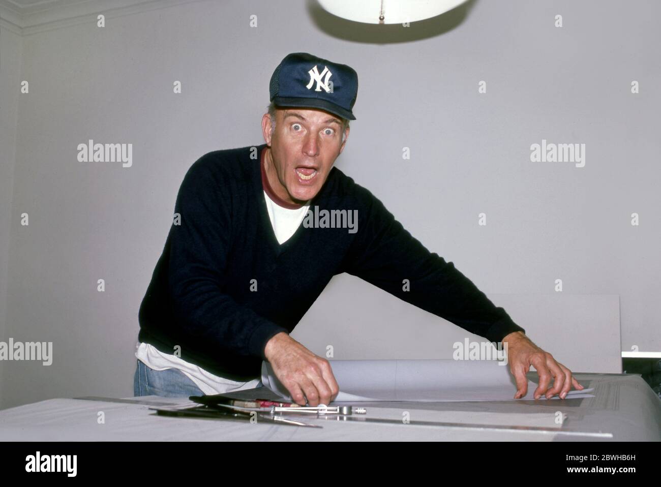 Künstler Robert Irwin trägt eine New York Yankees Baseballmütze bei der Arbeit auf dem Tisch in seinem Haus in Los Angeles, CA um 1983 Stockfoto