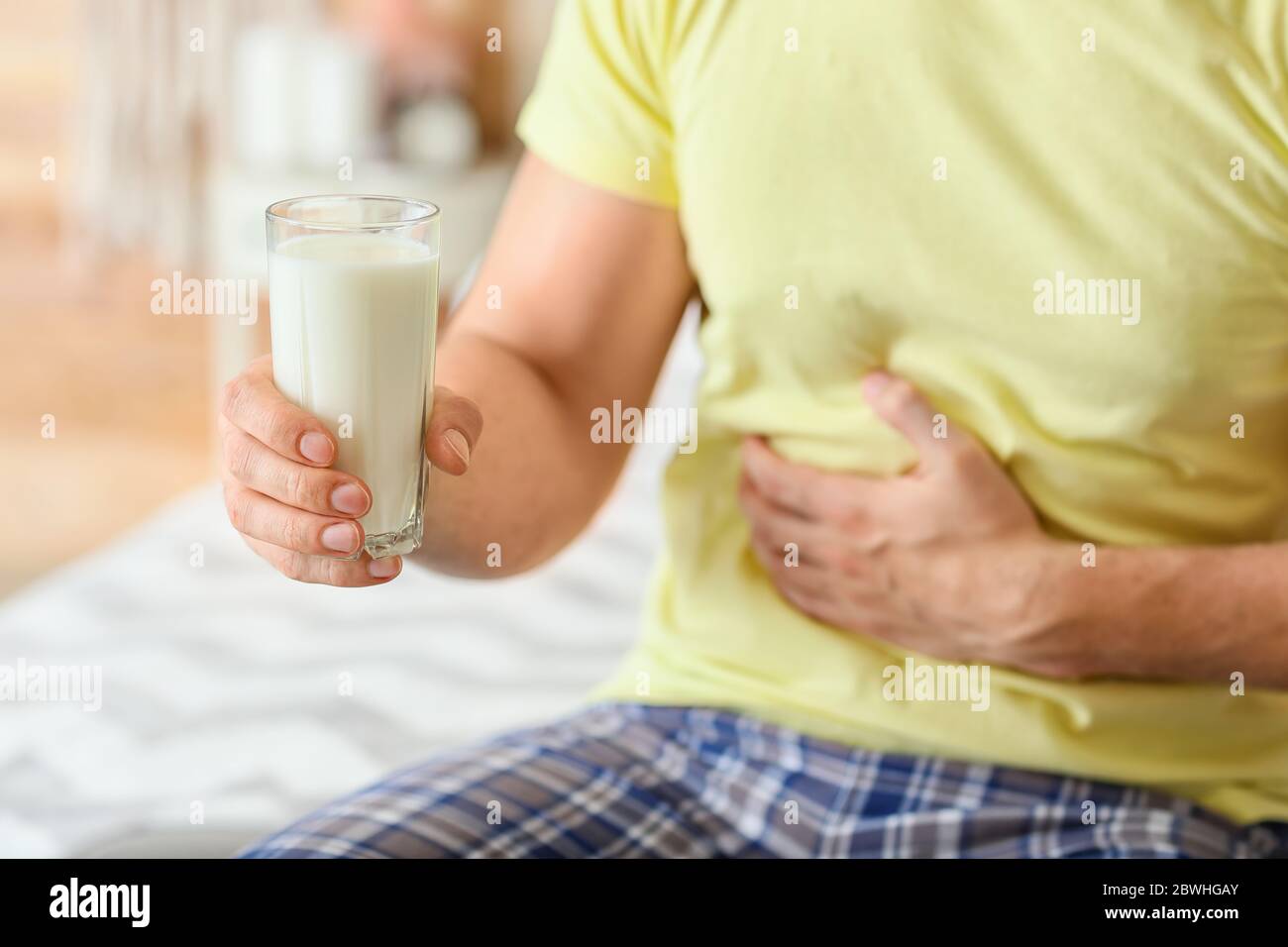 Junger Mann mit Milchallergie im Schlafzimmer Stockfoto