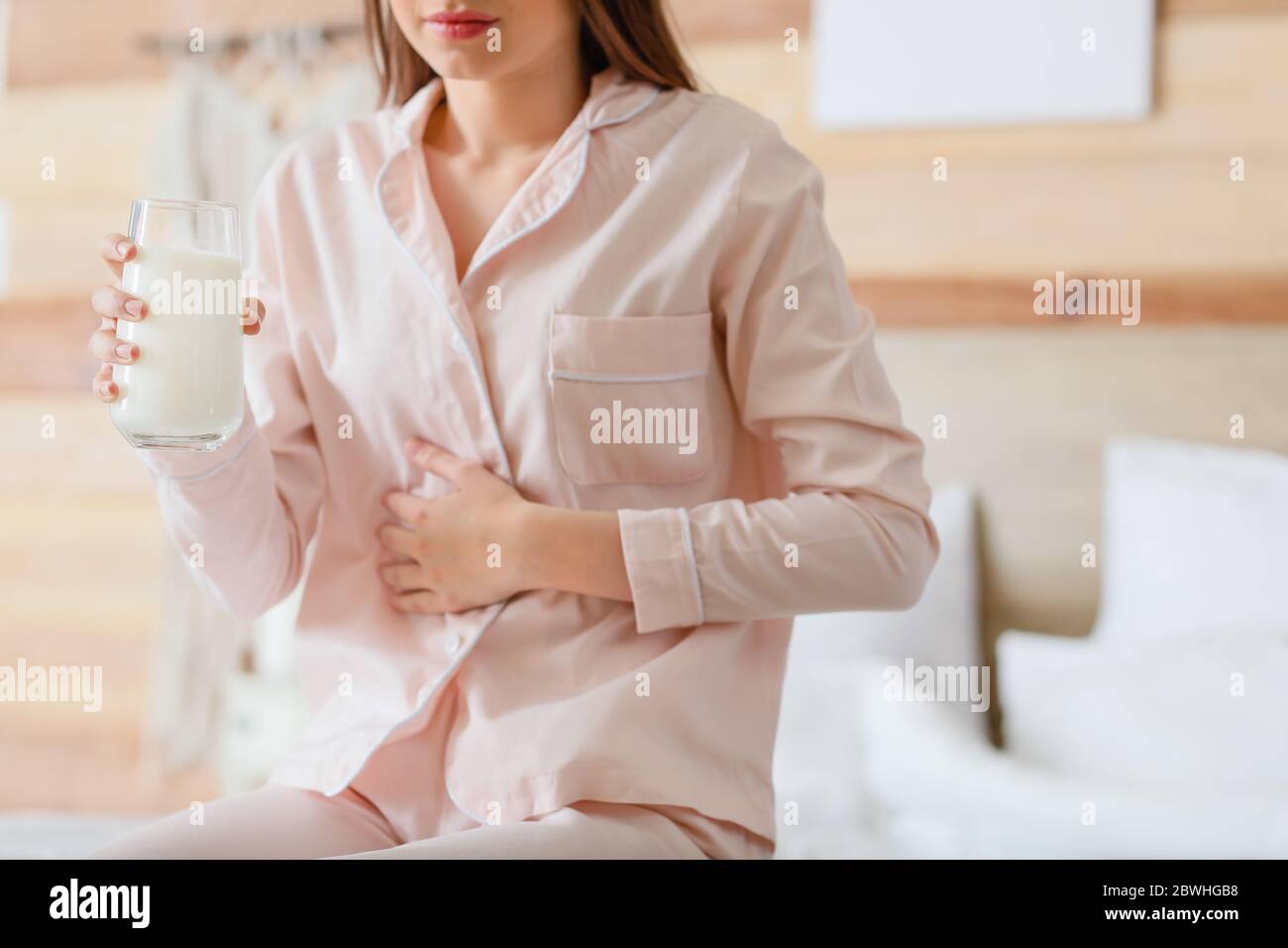 Junge Frau mit Milchallergie im Schlafzimmer Stockfoto
