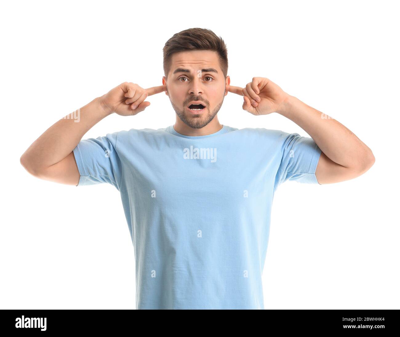 Junger Mann, der unter lauten Geräuschen auf weißem Hintergrund leidet