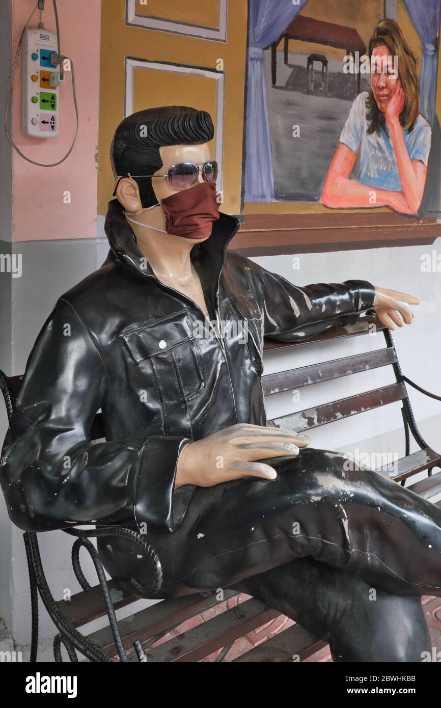 Während der Pandemie von Covid-19 (nCorona) im Jahr 2020 trägt eine sitzende Statue von Elvis Presley vor einem Café in Bangkok, Thailand, eine Gesichtsmaske Stockfoto