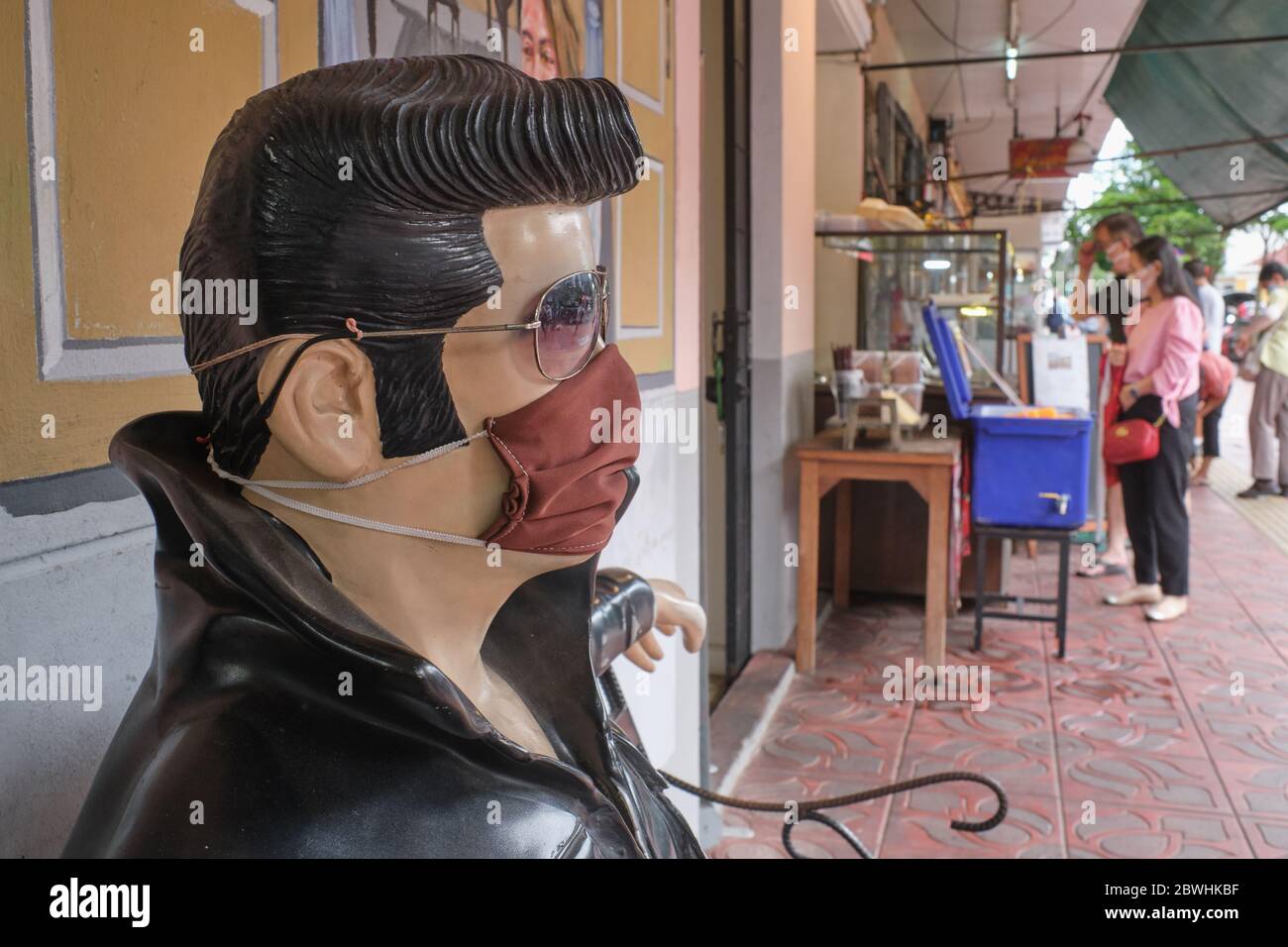 Während der Pandemie von Covid-19 (nCorona) im Jahr 2020 trägt eine sitzende Statue von Elvis Presley vor einem Café in Bangkok, Thailand, eine Gesichtsmaske Stockfoto