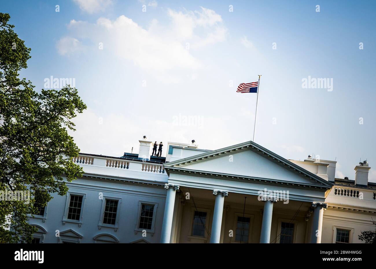 Das Weiße Haus mit zwei Sicherheitsmännern auf dem Dach mit Fernglas und US-Flagge auf den Kopf gestellt (Konzept der Not), Washington DC, USA. Stockfoto