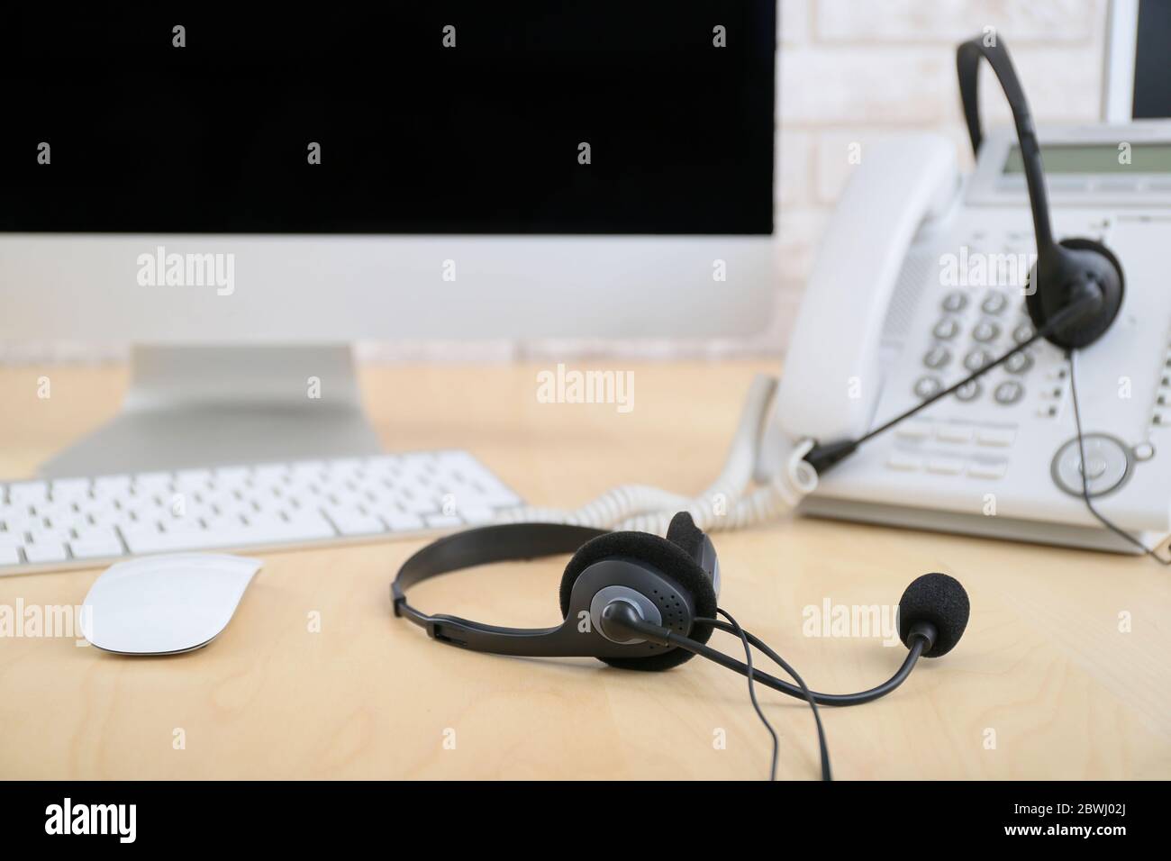 Headset und Computer mit Telefon auf dem Tisch des Agenten des technischen Supports im Büro Stockfoto