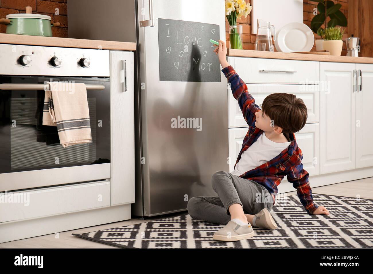 Kleiner Junge Schreiben Text Ich LIEBE MUTTER auf Tafel in der Küche Stockfoto