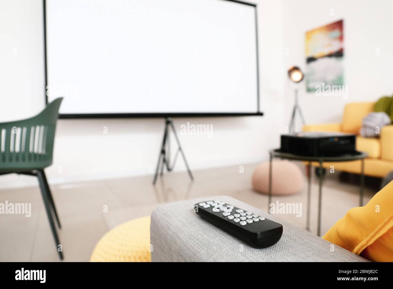 Fernbedienung auf Sofa im Zimmer mit Videoprojektor Stockfoto