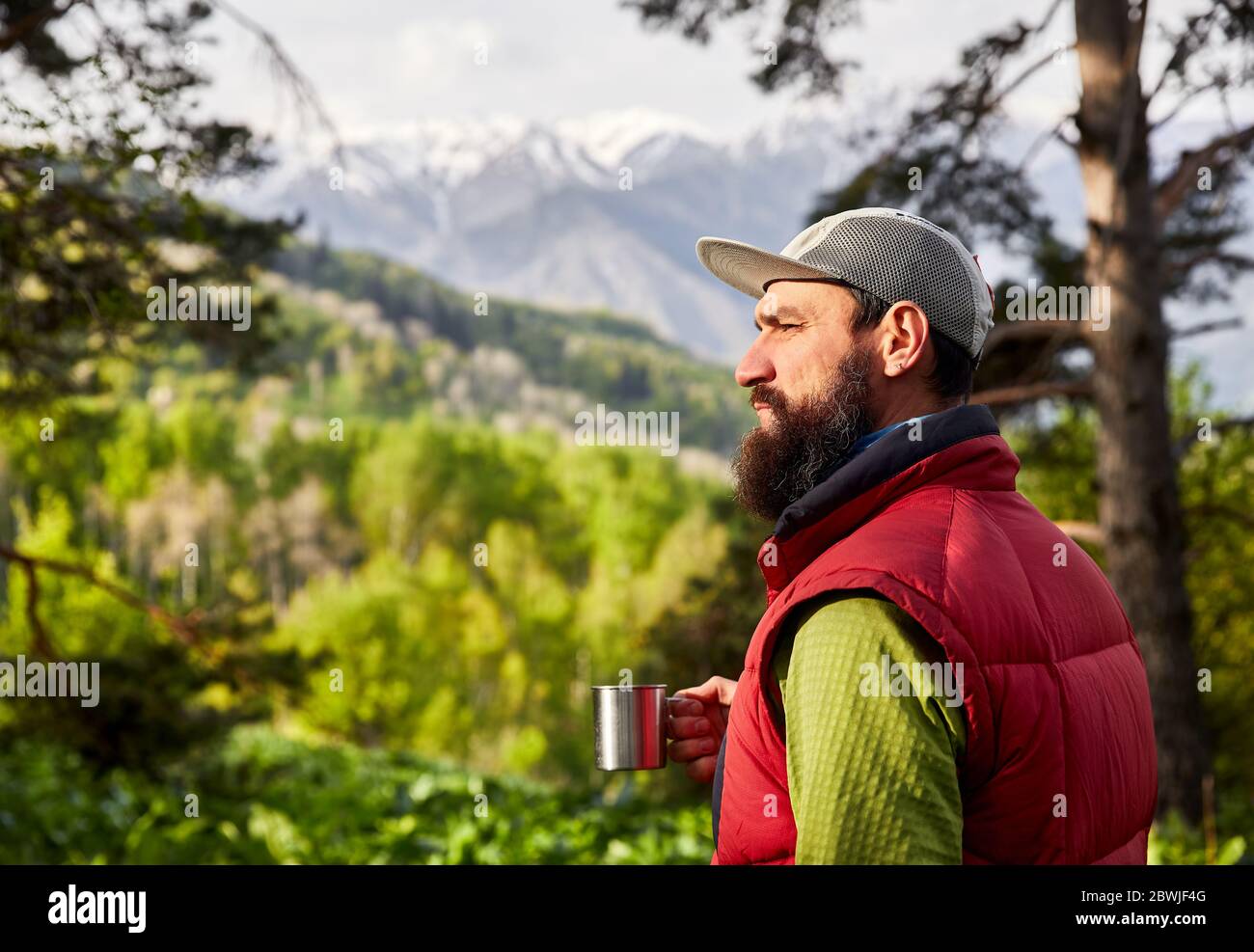 Porträt des bärtigen Touristen ist eine Tasse Kaffee in den üppigen Wald in den Bergen Stockfoto