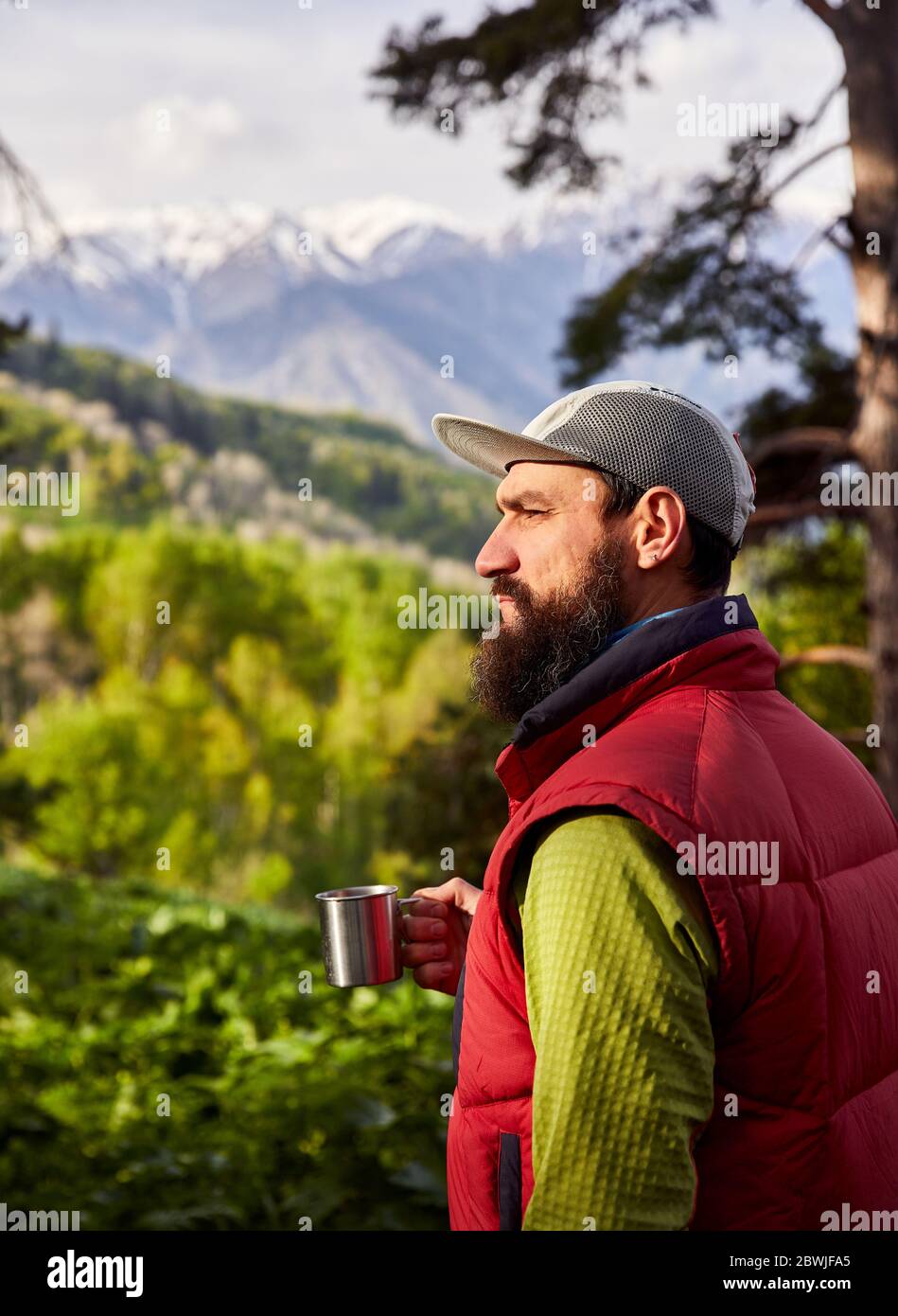 Porträt des bärtigen Touristen ist eine Tasse Kaffee in den üppigen Wald in den Bergen Stockfoto