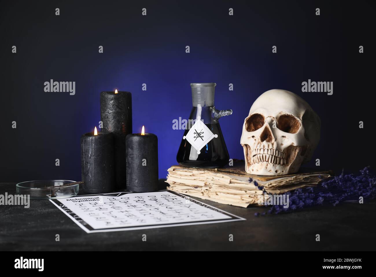 Tränke, menschlicher Schädel und altes Buch auf dem Tisch des Alchemisten Stockfoto