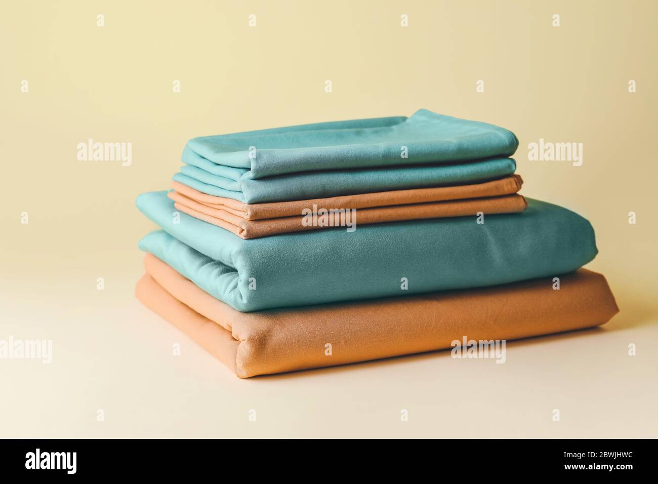 Stapel mit sauberer Bettwäsche auf farbigen Hintergrund Stockfoto