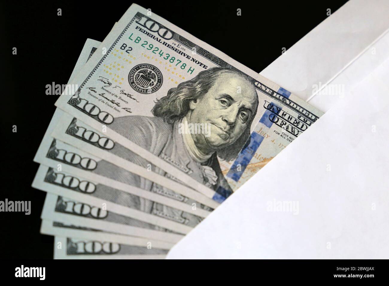 US-Dollar in weißem Umschlag auf schwarzem Hintergrund. Einkommen, Bonus oder Bestechung Konzept Stockfoto