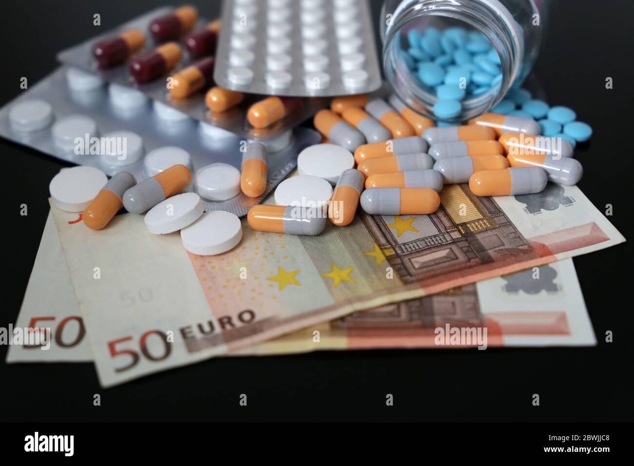 Pillen und Kapseln auf Euro-Rechnungen. Konzept der Gesundheitsversorgung, Pharmaindustrie, Arzneimittelpreise in der EU, Apotheke, Medizin und Wirtschaft Stockfoto