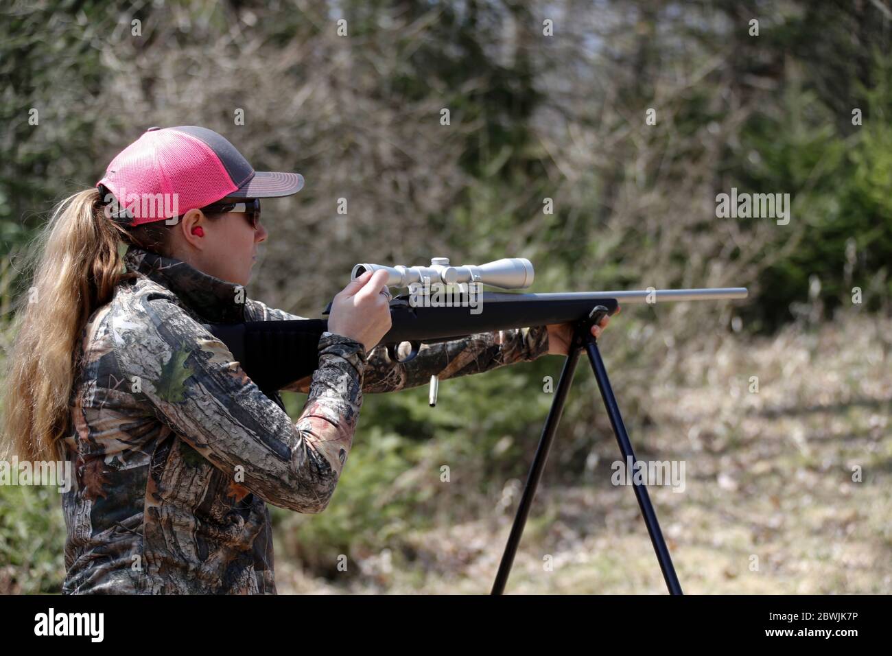 Frau Shooter wirft eine verbrauchte Schale aus einem Gewehr. Stockfoto