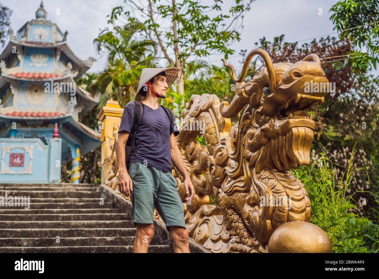 Junger Mann Tourist in einem traditionellen vietnamesischen Hut reist nach Vietnam Stockfoto